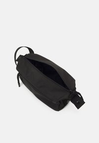 Bolsa negra con cremallera de forma rectangular, hecha de un material texturizado. Presenta un asa lateral y mínimos acentos de hardware.