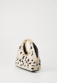Triangle-shaped handbag in beige fabric with black spots, featuring two gold circular handles and a black interior lining.