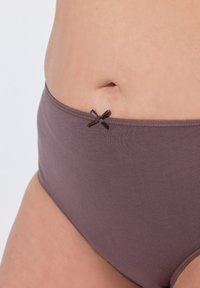 Höga bruna underkläder med en slät textur, prydda med en liten mörk rosett vid midjan.