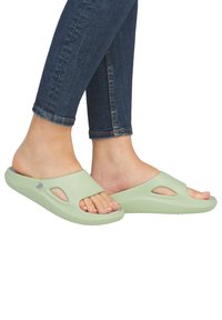 Sandales vertes à enfiler avec design découpé, fabriquées en matériau flexible. Elles possèdent une semelle extérieure texturée et un logo sur le côté.