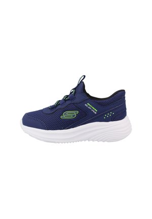 Zapatilla Skechers azul marino con detalles verdes, suela blanca gruesa, parte superior de malla, tirador en la lengüeta y diseño sin cordones.
