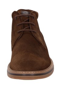 Stivaletti in suede marrone alla caviglia con punta rotonda, dettagli in pelle e lacci marroni. Suola in gomma con bordo beige a contrasto. Design semplice e privo di ornamenti.