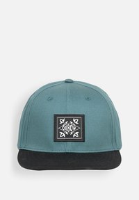 Casquette bleu-vert avec visière noire, ornée d'un logo blanc brodé sur un patch rectangulaire. Fabriquée en tissu avec une texture lisse.