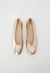 Ballet flats metallici oro con una finitura liscia, punta rotonda e un interno imbottito. Marchio Gabor visibile sulla soletta.