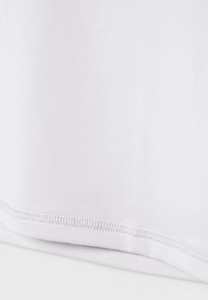 Nærbillede af en hvid stofkant med pæn dobbeltsyning og foldet kant på en ensfarvet hvid baggrund.