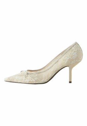 Ivory high-heeled pump with pointed toe, covered in floral lace and adorned with a small bow on top.