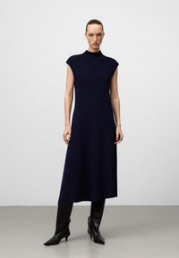 Abito midi senza maniche di color navy con collo alto, realizzato in un tessuto testurizzato, caratterizzato da una vestibilità rilassata e che arriva fino a metà polpaccio.