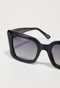 Svarta fyrkantiga solglasögon med gradientlinser. Tjock, djärv ram med slät yta. Inkluderar varumärkets detalj på bågen. Kategori 2 UV-skydd.