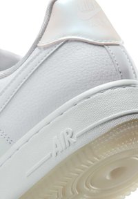 Sneaker bianca in pelle con tomaia strutturata, dettagli lucidi e suola in gomma traslucida. Presenta il logo "AIR" in rilievo sul lato.