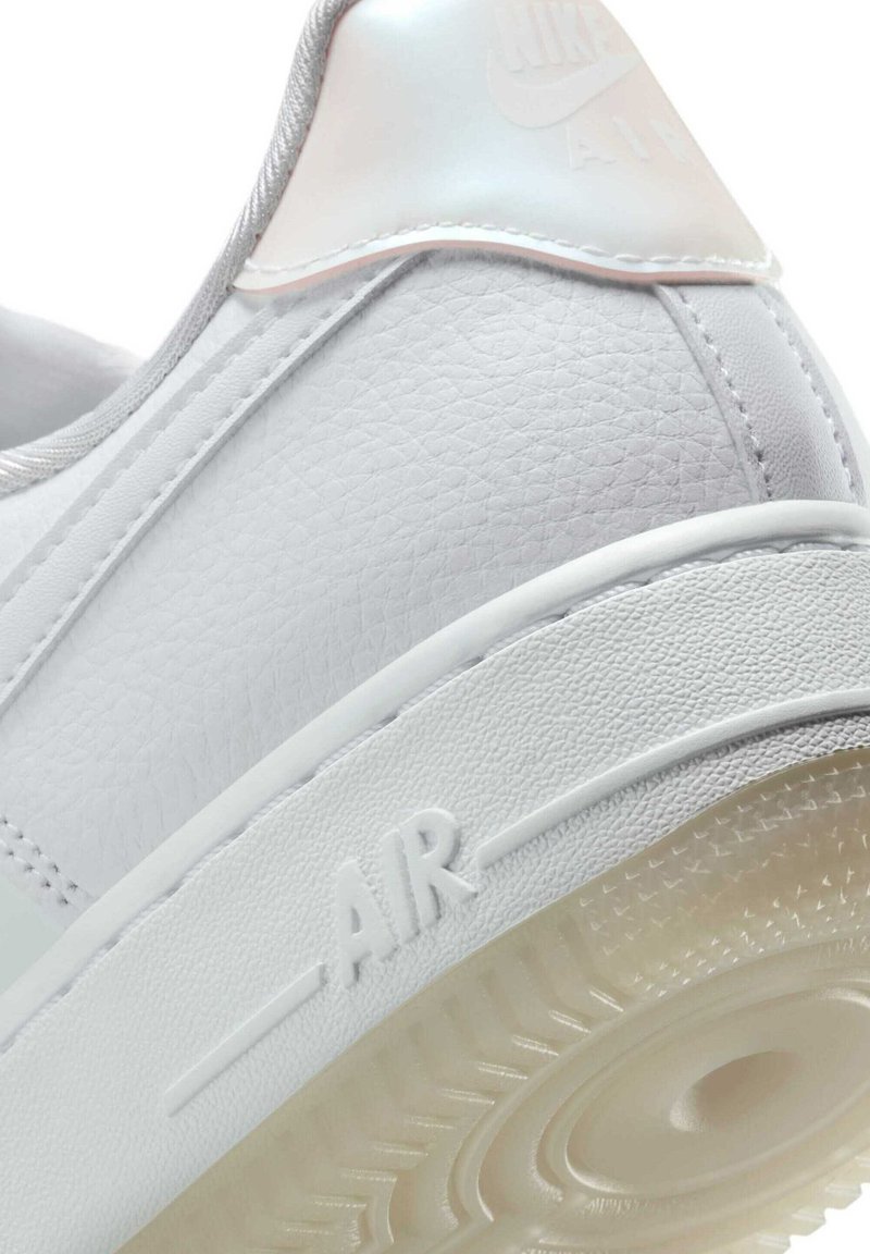 Witte leren sneaker met gestructureerd bovenwerk, glanzende accenten en een doorzichtige rubberen zool. Heeft een verdiept 'AIR' logo aan de zijkant.