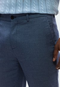 Προσαρμοσμένο παντελόνι σε ναυτικό μπλε με υφή ύφασμα, διαθέτει επίπεδη μπροστινή όψη, πλαϊνές τσέπες και κούμπωμα με κουμπί στη μέση.