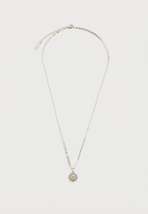 Collar de cadena plateada con un colgante en forma de sol que presenta un diseño detallado de un rostro, colocado plano sobre un fondo blanco.