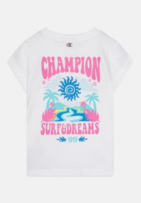 Valge lühikeste varrukatega T-särk, millel on värvikas graafika päikesest, palmipuudest ja jõest koos tekstiga "CHAMPION SURF&DREAMS 1919".