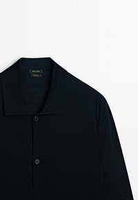 Black short-sleeve shirt with a notch collar, made of lightweight fabric. Features a button front and smooth texture with a simple design.