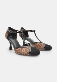 Čevlji z visokimi petami v leopardjem vzorcu z akcenti iz črnega umetnega sijočega usnja ter T-strap obliko, ki vključuje konično nos figure in teksturirano blago.