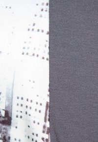 Dwa paneli materiałowe: jeden z monochromatycznym nadrukiem miejskim w czerni i bieli, drugi w jednolitym ciemnoszarym kolorze. Teksturowane powierzchnie.