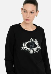 Zwarte sweatshirt met een bloemen- en logoontwerp in het midden, gemaakt van een katoenmix met een klassieke ronde hals.
