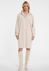 Beiges Corduroy-Hemdkleid mit durchgehender Knopfleiste, Kragen und einer Brusttasche; verfügt über lange, leicht geraffte Ärmel und eine lockere Passform.