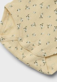 Gul ribbad baby bodysuit med blommönster, som har tryckknappar i botten för enkel påklädning och mjuk textur.