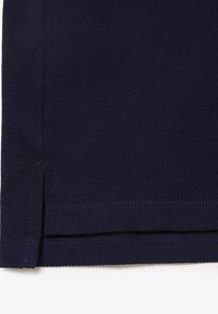 Granatowy materiał o teksturowanej powierzchni, z prostym dołem i bocznymi rozporkami dla lepszej swobody ruchów. Gładkie wykończenie szwów na krawędziach.