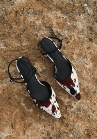 Purnu purngala kurpes ar govs ādas rakstu, kas satur balto, brūno un melno krāsu maisījumu. Melni potītes siksnas, gluda iekšējā oderējums.