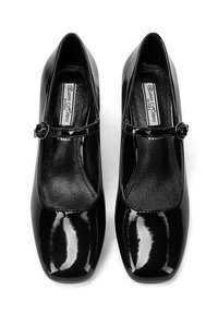 Scarpe Mary Jane in vernice nera con punta quadrata, tacco piatto e cinturino laterale con fibbia. L'interno ha una finitura liscia.