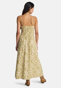 Μάξι φόρεμα σε ελιά πράσινο με floral σχέδιο, με κορσέ με σφηκοφωλιά, λεπτές ρυθμιζόμενες τιράντες και αέρινη φούστα.