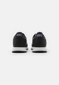 Sorte atletiske sko med en glatt stoffoverdel, lilla detaljer og en hvit mellomsåle, som viser polstret design og ASICS-merke.
