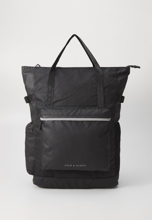 Sort nylon tote bag med dobbel top-håndtag, justerbare stropper, frontlomme med lynlås med reflekterende stribe og logo-tryk nederst.