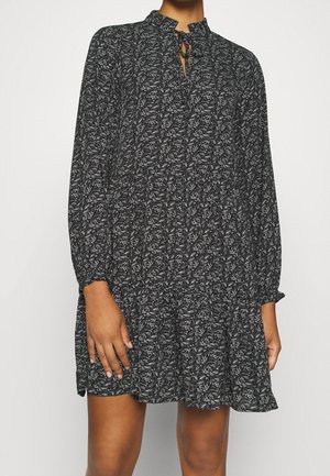 Czarna sukienka w kwiatowy wzór z długimi rękawami, falowanym dołem, wysokim kołnierzem i wiązaniem. Wykonana z lekkiego materiału.