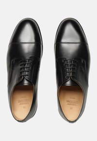 Chaussures habillées en cuir noir avec une finition lisse, dotées d'un bout arrondi, d'un laçage et de subtils accents cousus sur le devant.