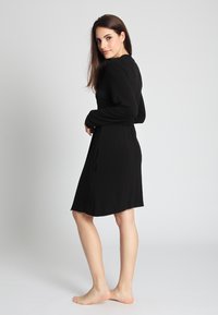 Schwarz, langärmliges Kleid mit taillierter Taille und schwingendem Rock, aus weichem Stoff mit glatter Textur, knielang.