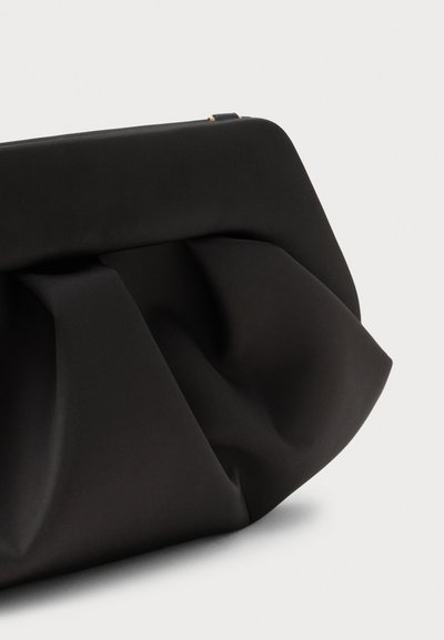 Svarte clutch-veske laget av glatt stoff, med en plisserte design og skrå kanter, med en diskret gullglidelås og minimalistisk estetikk.