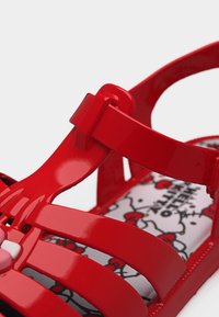 Κόκκινο γυαλιστερό παιδικό σανδάλι με ρυθμιζόμενο λουράκι και εσωτερική σόλα με μοτίβο Hello Kitty.
