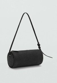 Bolso cilíndrico negro con textura suave, decorado con lunares blancos, una correa delgada y cierre de cremallera en la parte superior.