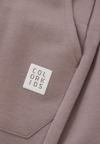 Ljuslila sweatshirt med strukturerad tyg, med ett broderat vitt fyrkantigt märke som visar varumärket "COLOR KIDS."