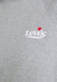 Sweatshirt gris avec un col rond. Présente un logo Levi's blanc et un cœur rouge au-dessus du logo. Texture douce, coupe décontractée.