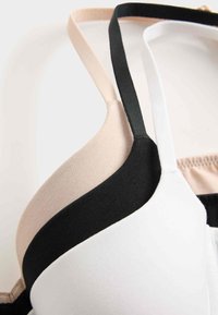 BH van zachte stof met verstelbare bandjes in zwart, nude en wit. Het heeft een naadloos ontwerp en is gedeeltelijk gevoerd.