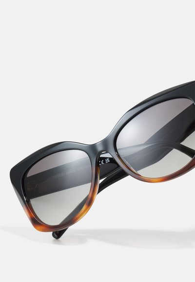Black and tortoiseshell sunglasses with oversized cat-eye frames and gradient gray lenses. Textured finish with metal accents inside the arms.
