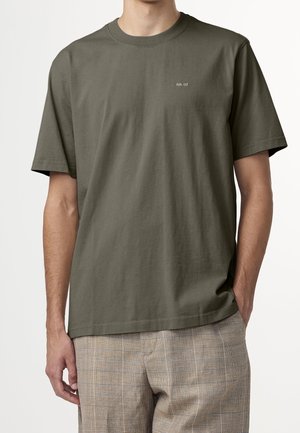 Olivengrünes Baumwoll-T-Shirt mit Rundhalsausschnitt und kurzen Ärmeln. Mit kleinem Text-Logo "N.N. 07" auf der Brust. Angenehme, glatte Textur.