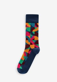 Chaussette en coton colorée avec un motif géométrique incluant des sections orange, rose, vert et bleu marine, terminée par un bord bleu marine uni.