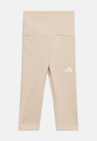 Μπεζ κολάν ψηλόμεσο, κομμένο, με λευκό λογότυπο Adidas στον αριστερό μηρό, απλωμένο επίπεδα σε λευκό φόντο.