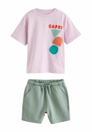 Svetloružový bavlnený tričko s farebnými geometrickými potlačami a slovom "CAPRI" v kombinácii so zelenými bavlnenými šortkami s elastickým pásom.