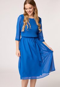 Blauwe jurk met een geplooide top, driekwart doorzichtige mouwen en een vloeiende rok met een tailleband. Soepele textuur, lichtgewicht stof.