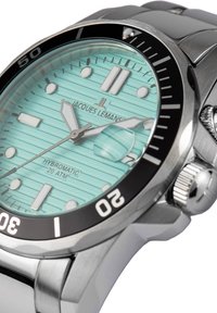 Montre en acier inoxydable argenté avec un cadran texturé vert menthe, une lunette noire avec des index blancs, des aiguilles lumineuses et une fenêtre de date.