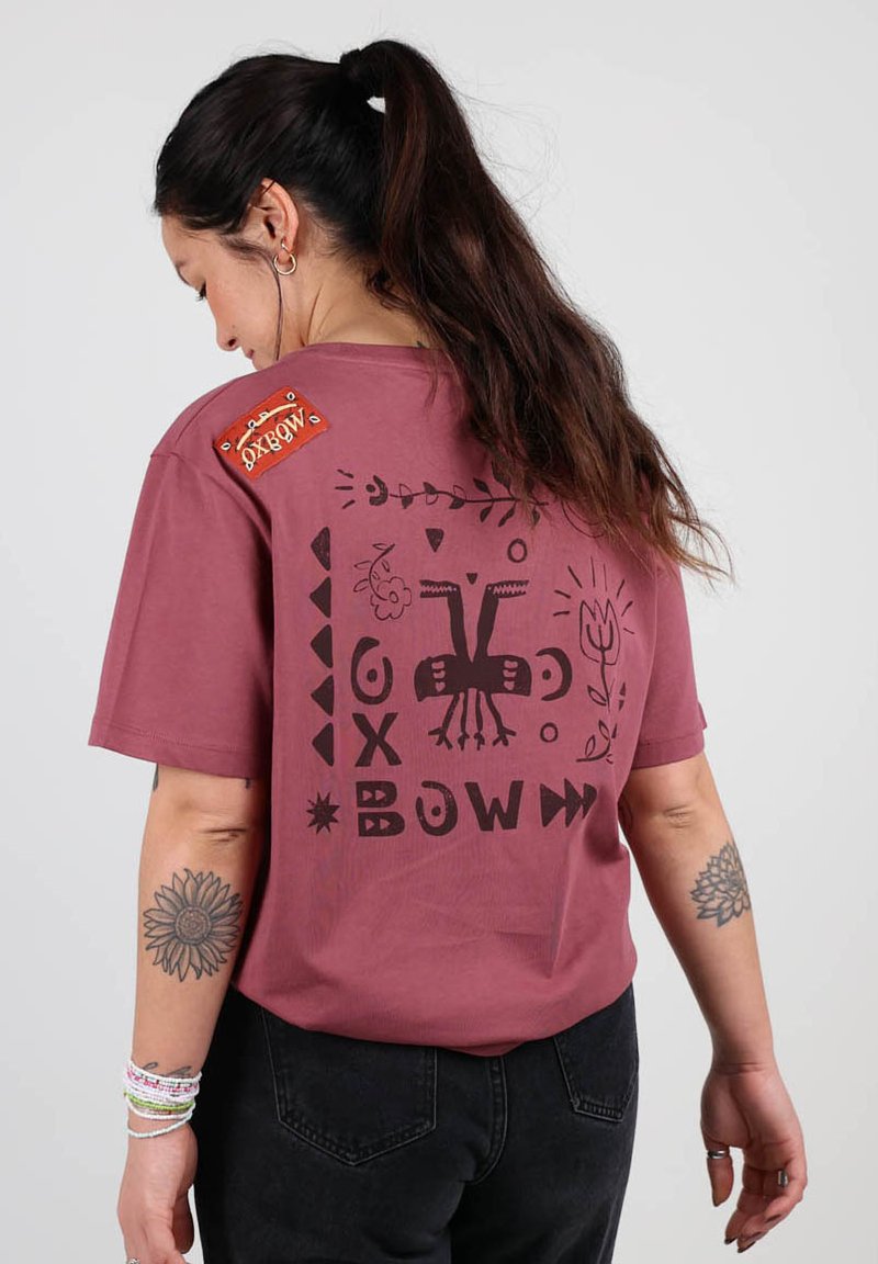 T-shirt en coton bordeaux avec un design graphique noir comprenant des formes et des motifs abstraits à l'arrière ; comprend une étiquette rouge sur l'épaule.