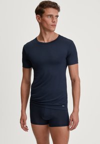 Navy blue cotton t-shirt with short sleeves, round neckline, and smooth texture. Paired with matching navy brief shorts featuring a logo tag.