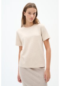 Beige tričko s krátkým rukávem vyrobené z měkké tkaniny, s kulatým výstřihem a uvolněným střihem, spárované s béžovou žebrovanou sukní. Hladká textura.
