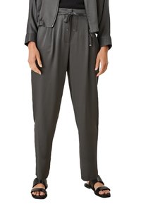 Grijze lichte broek met een elastische tailleband en koord. Ontworpen in een losse pasvorm met taps toelopende pijpen, gecombineerd met zwarte sandalen.