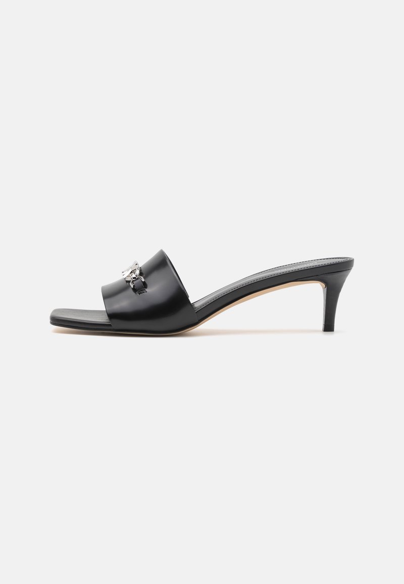 Mule en cuir noir à enfiler avec un talon kitten de taille moyenne et une chaîne décorative argentée sur la bride, vue de profil sur fond blanc.